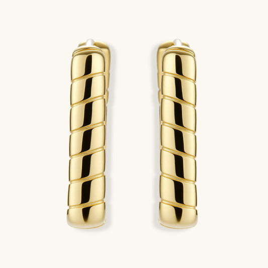 Chunky segmented gold-plated huggie hoop earrings with bamboo-inspired geometric design on white background.
