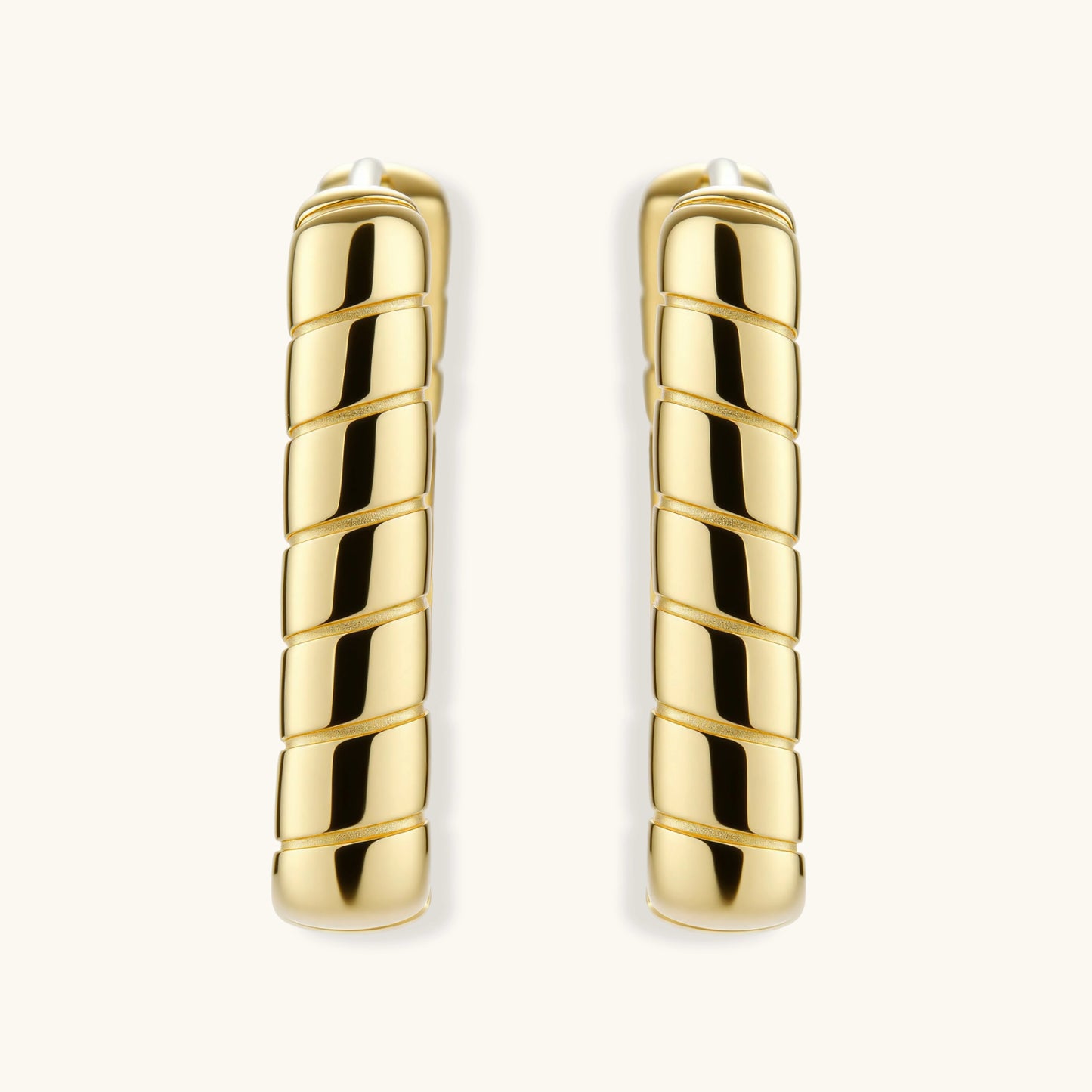 Chunky segmented gold-plated huggie hoop earrings with bamboo-inspired geometric design on white background.