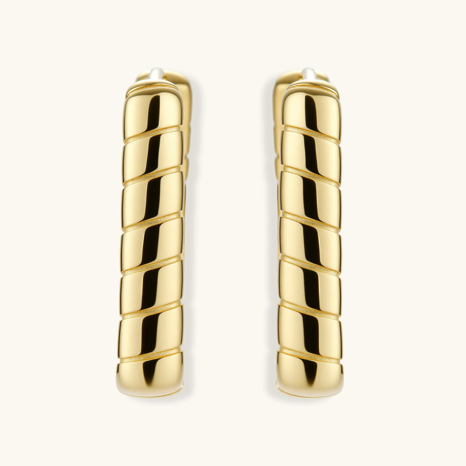 Chunky segmented gold-plated huggie hoop earrings with bamboo-inspired geometric design on white background.