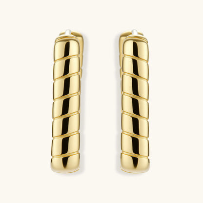 Chunky segmented gold-plated huggie hoop earrings with bamboo-inspired geometric design on white background.