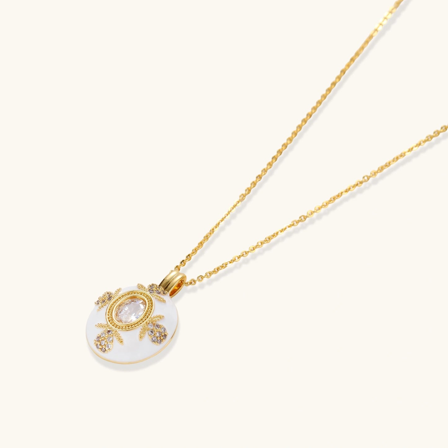 Gold-plated necklace with circular white enamel pendant featuring central zirconia stone and ornate decorative details